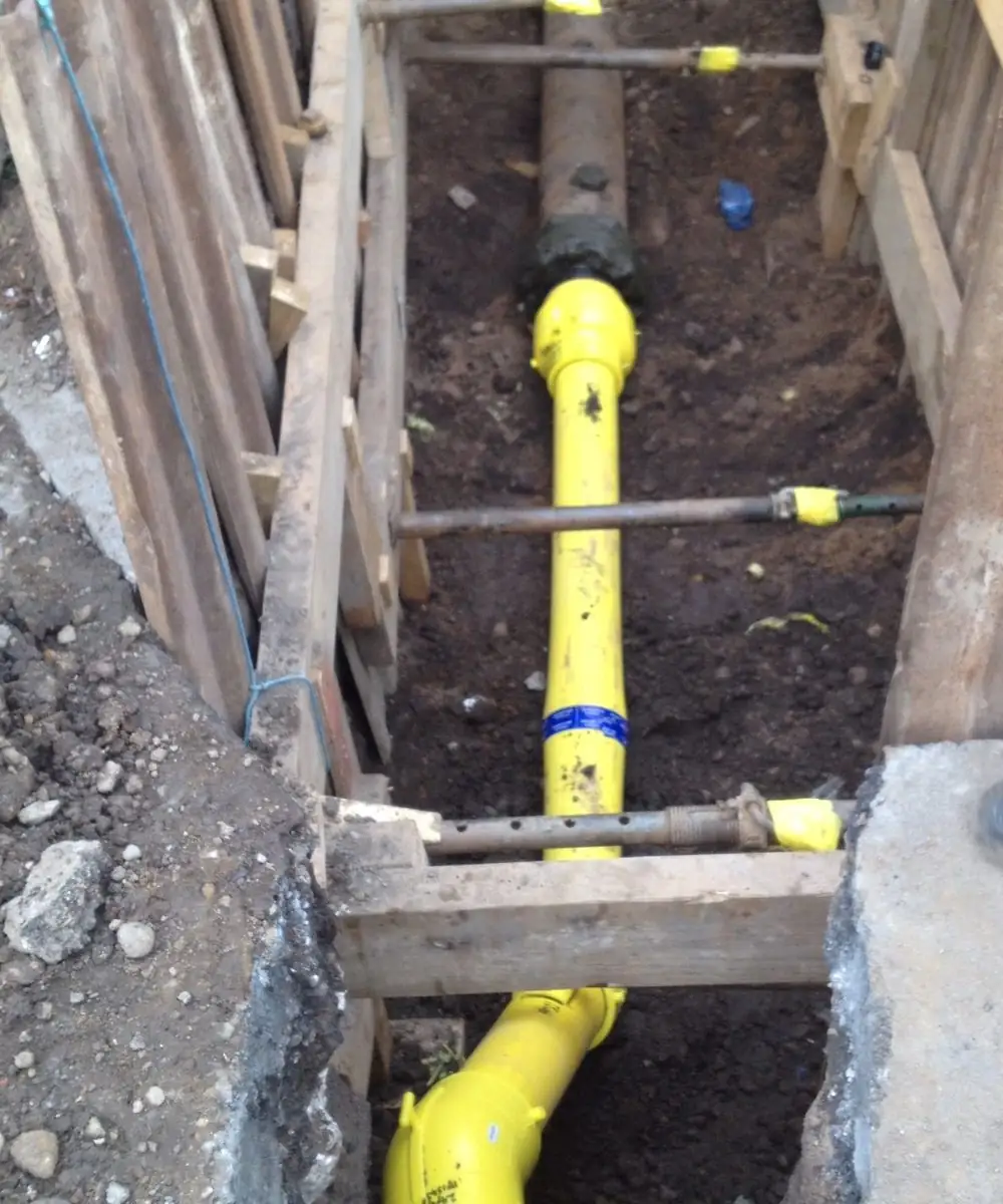 New yellow PE main and service tees laid in a timber-shored trench