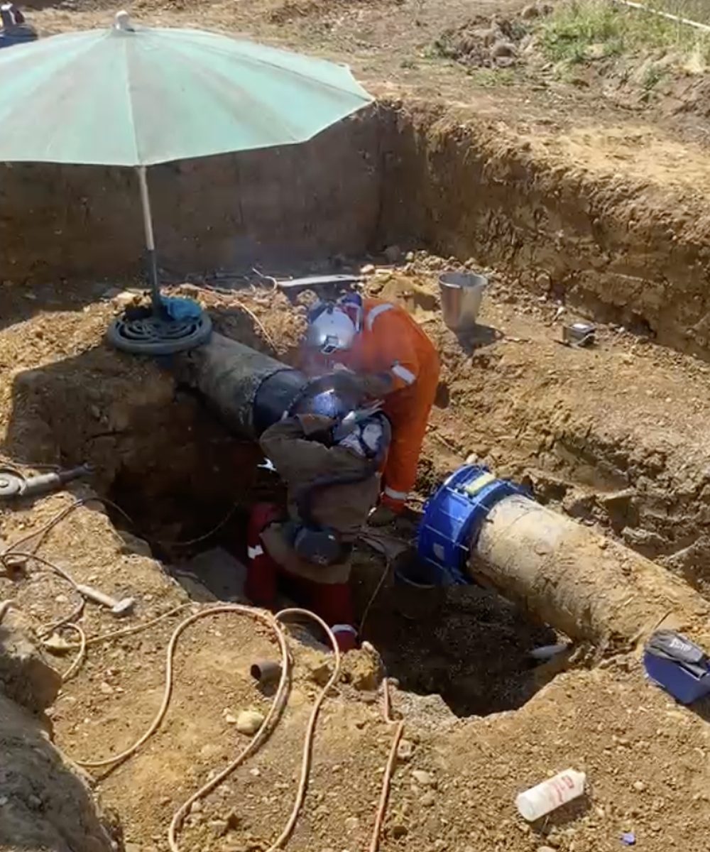 Operative carrying out hot works on a steel gas main in an open excavation
